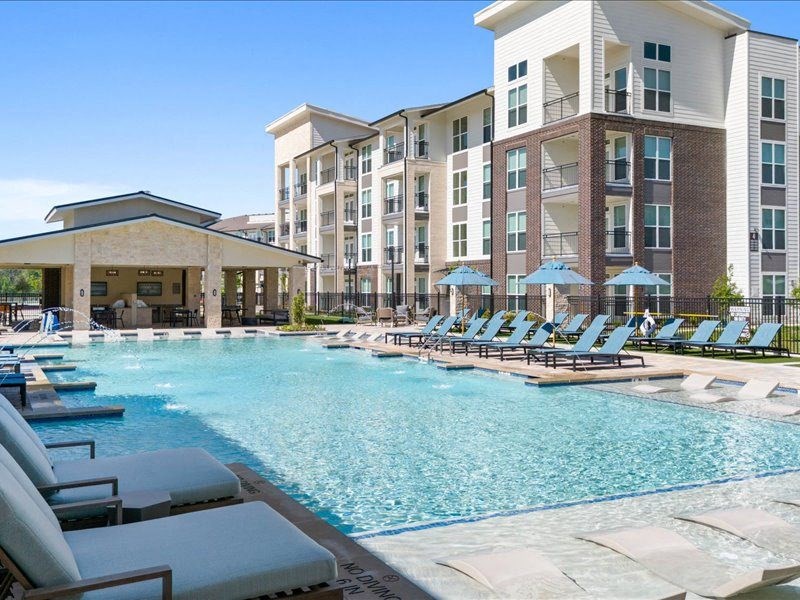 a large swimming pool with lounge chairs and a building
