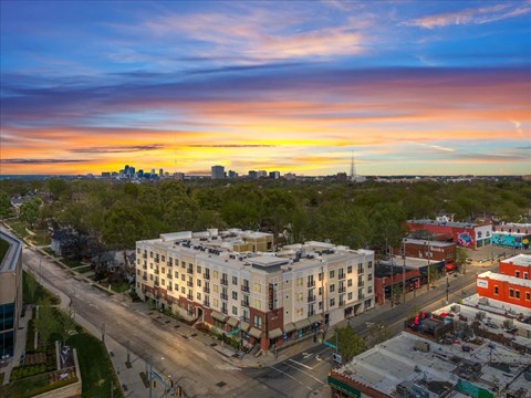 Aerial view of West 39th Apartments and surrounding Kansas City neighborhood with skyline in background at sunset.