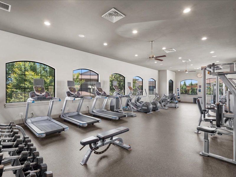 a gym with cardio equipment and windows