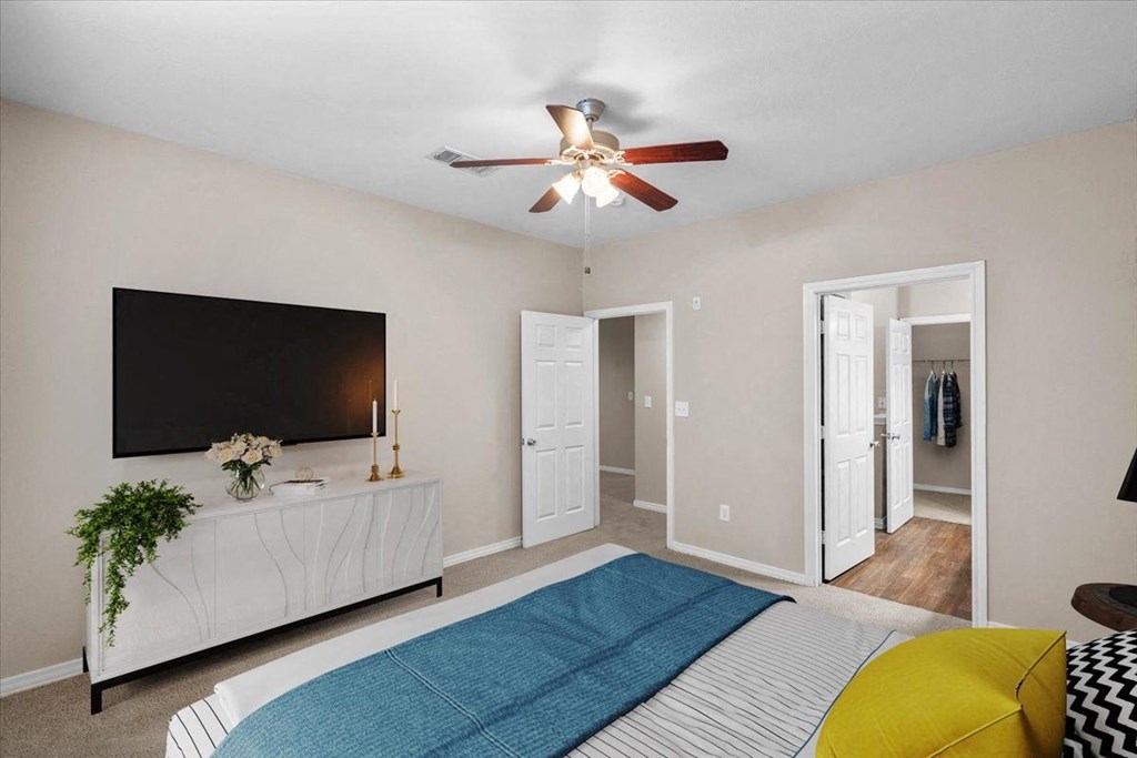 a bedroom with a bed and a ceiling fan at The Clairborne Apartment Homes, Texas