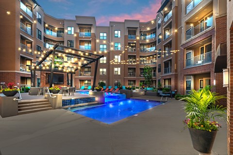 A large outdoor pool area with a hot tub and lounge chairs at a residential building.