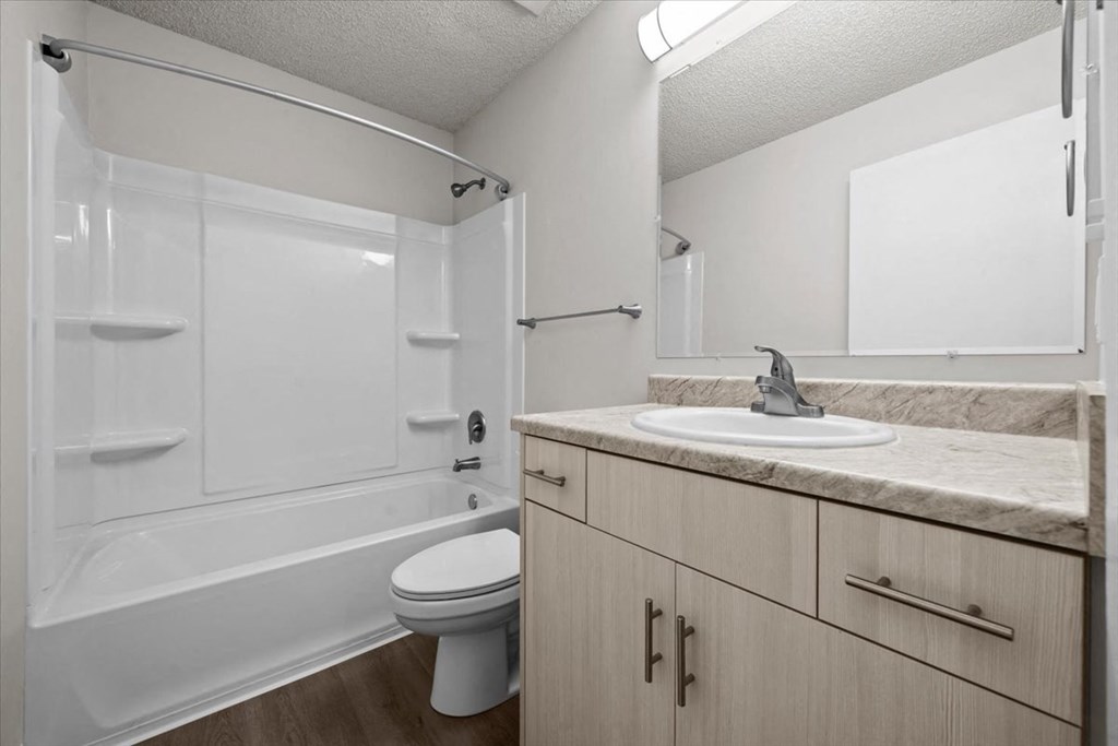 A white bathroom with a toilet, sink, and shower at Cloverset Active Adult Apartments, Missouri, 64114