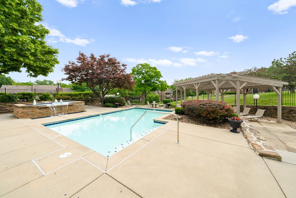 A pool surrounded by a patio and trees. at Coventry Oaks Apartments, Overland Park 66214