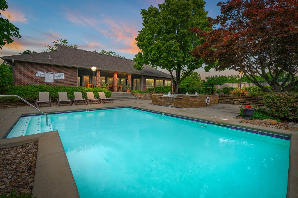 A swimming pool in front of a house with trees around. at Coventry Oaks Apartments, Overland Park, KS