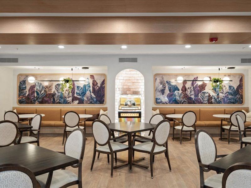 a restaurant with tables and chairs and paintings on the wall