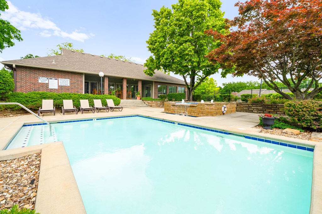 A swimming pool in front of a house with trees. at Coventry Oaks Apartments, Overland Park, KS, 66214
