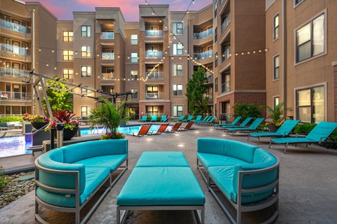 A large outdoor seating area with blue couches and a pool in the foreground.