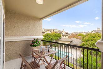 a balcony with a table and chairs and a pool in the background - Photo Gallery 3