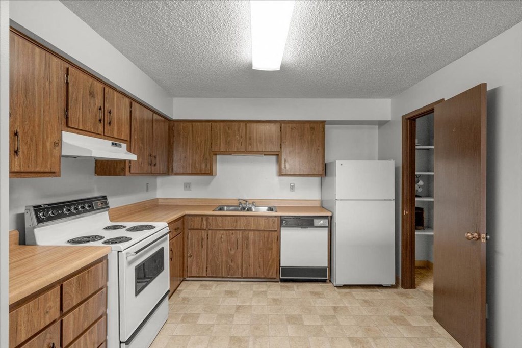 an empty kitchen with white appliances and wooden cabinets