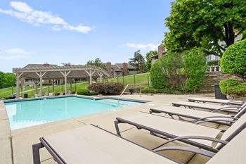A pool with sun loungers and a pavilion in the background. at Coventry Oaks Apartments, Kansas, 66214