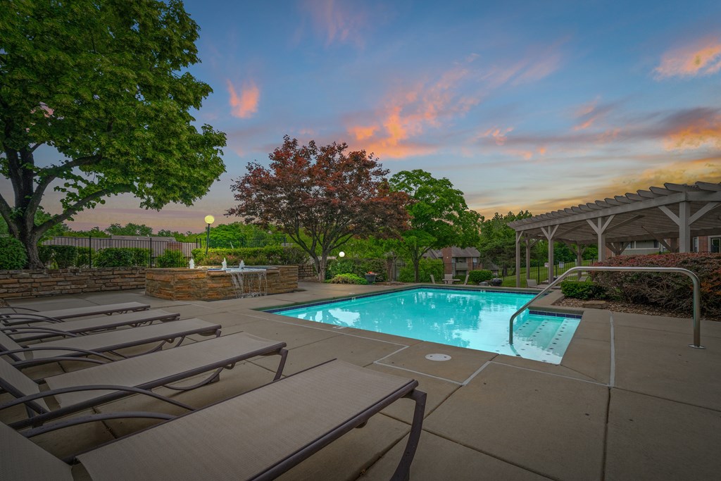 A pool surrounded by trees and lounge chairs at Coventry Oaks Apartments, Overland Park, KS, 66214