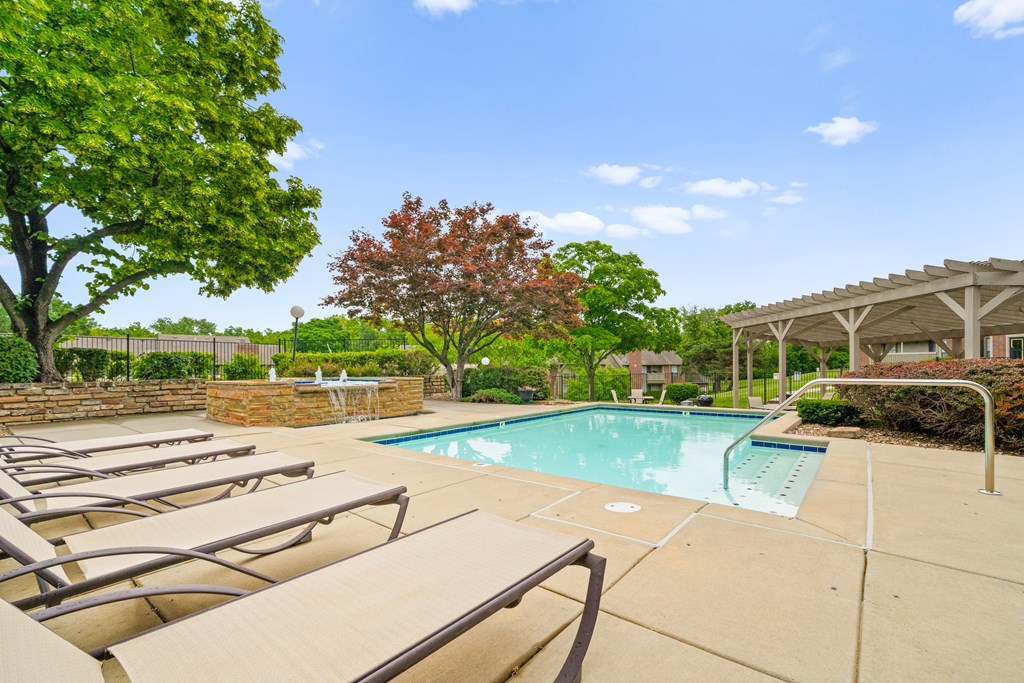 A pool surrounded by trees and chairs. at Coventry Oaks Apartments, Overland Park, KS, 66214