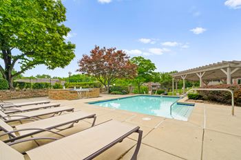 A pool surrounded by trees and chairs. at Coventry Oaks Apartments, Overland Park, KS, 66214
