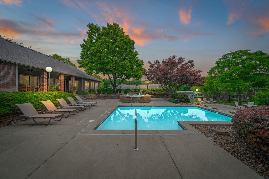 A swimming pool surrounded by lounge chairs and trees at Coventry Oaks Apartments, Overland Park 66214