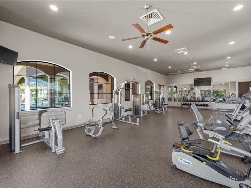 a gym with various exercise machines and a ceiling fan