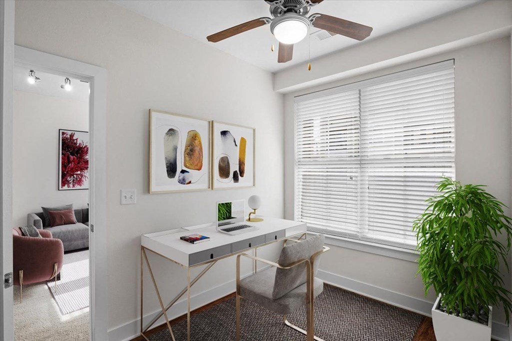 a home office with a ceiling fan and a large window