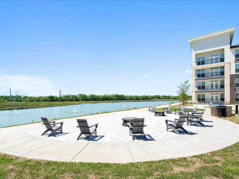 a swimming pool with patio furniture next to a building