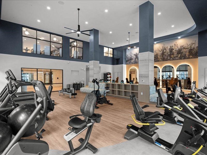 a gym with cardio equipment and weights on a wooden floor