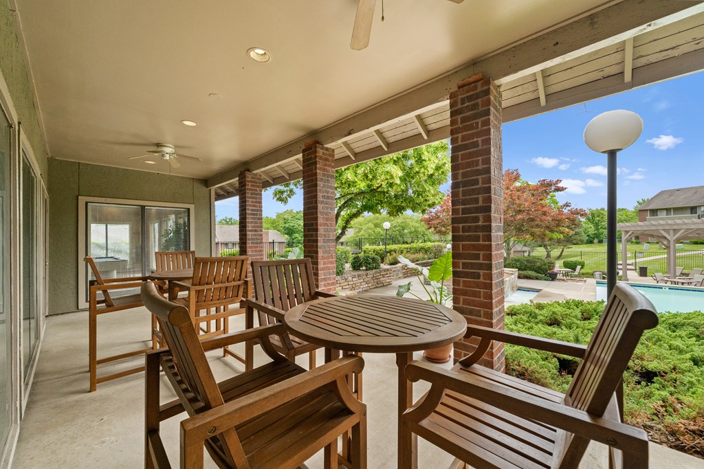 A patio with a table and chairs overlooking a pool at Coventry Oaks Apartments, Kansas