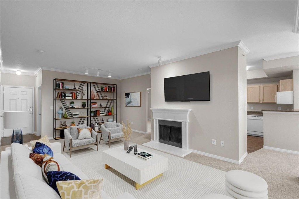 a living room with a fireplace and a bookshelf at The Clairborne Apartment Homes, Texas