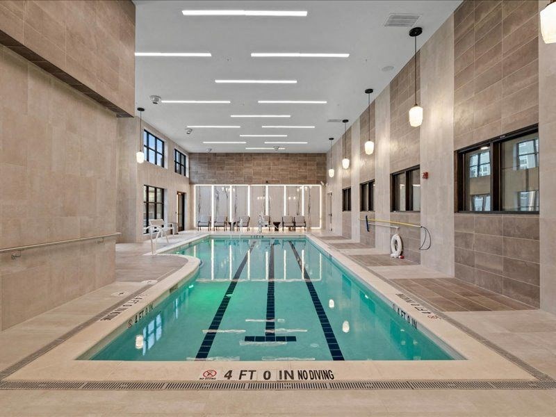 a swimming pool in the middle of a large room with tile flooring and walls