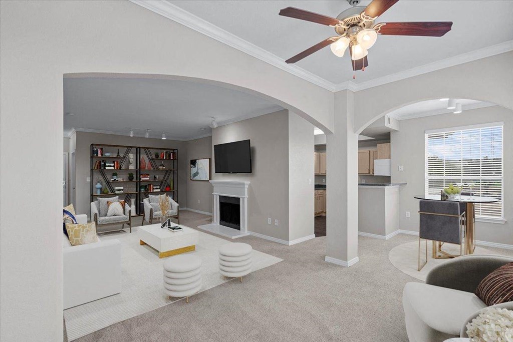 a living room with a fireplace and a ceiling fan at The Clairborne Apartment Homes, Texas