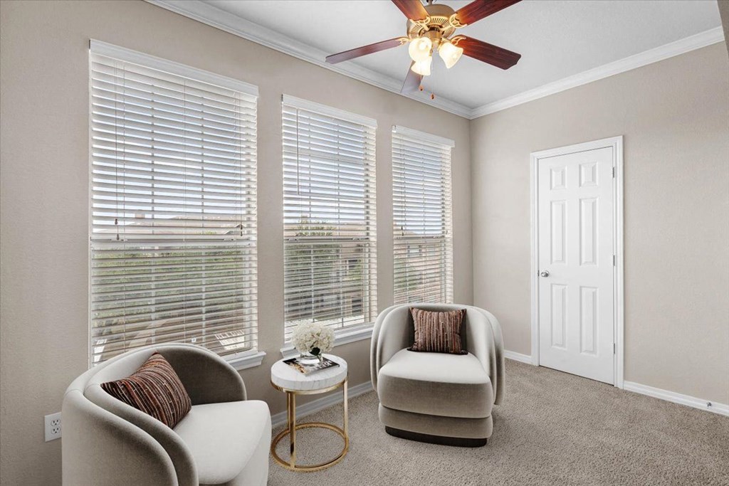a living room with three windows and a ceiling fan at The Clairborne Apartment Homes, Grand Prairie, TX