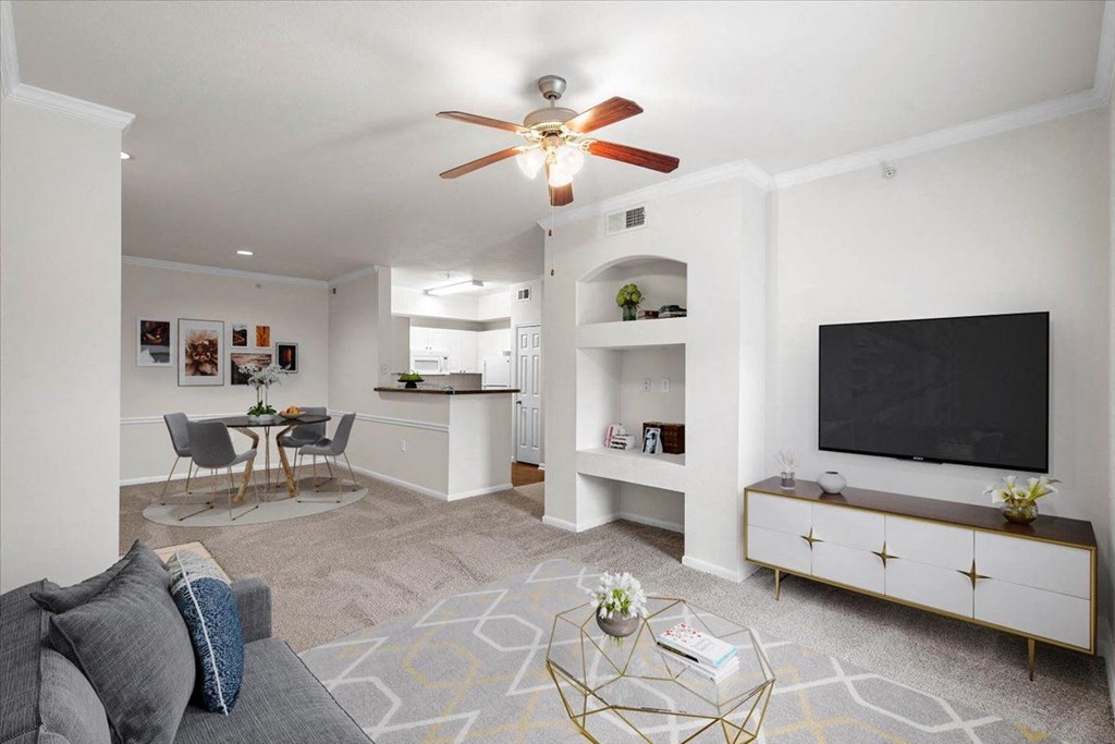 a living room with a ceiling fan and a flat screen tv