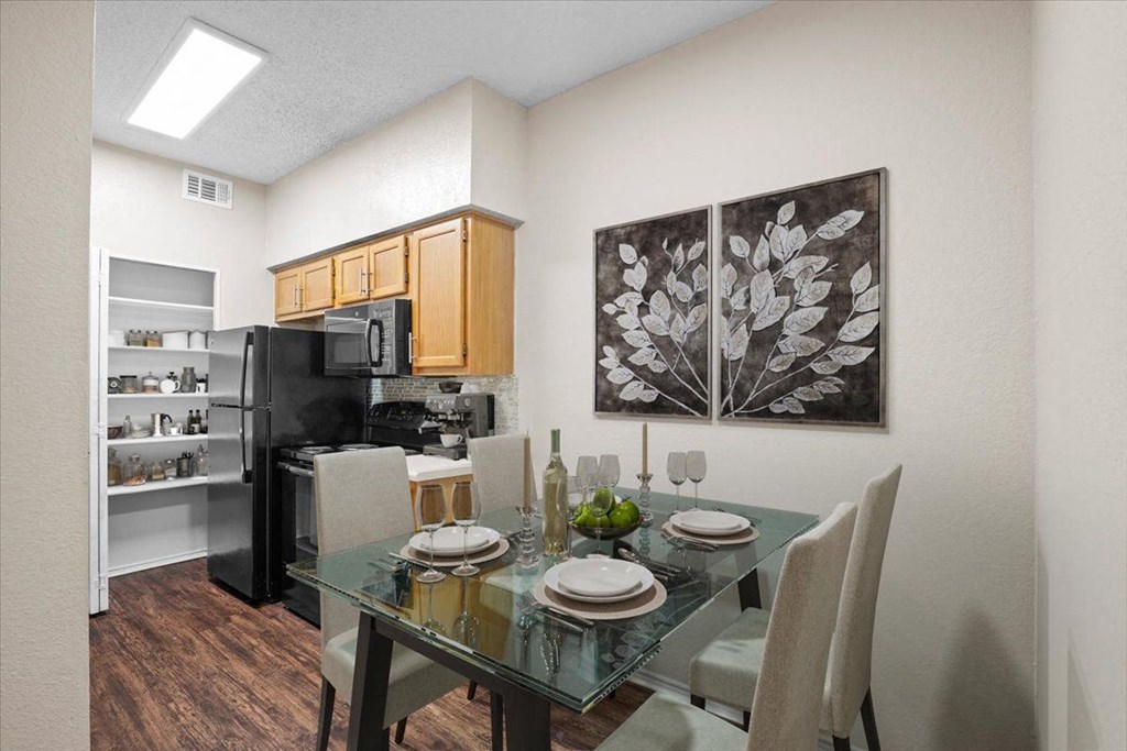 a dining area with a glass table and chairs and a kitchen in the background at Creekview Apartment Homes, Texas