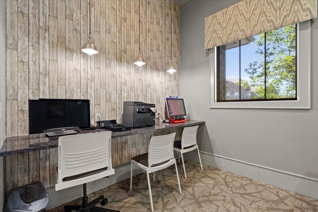 a room with two desks and two chairs with a computer monitor and printer on top of them