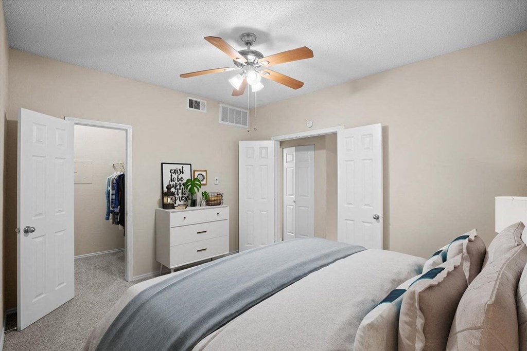 a bedroom with a large bed and a ceiling fan at Creekview Apartment Homes, Dallas, 75254