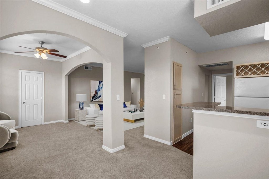 a living room and kitchen area with a ceiling fan at The Clairborne Apartment Homes, Grand Prairie