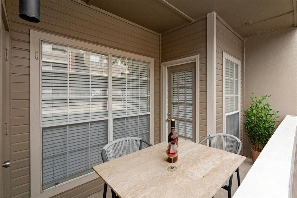 a patio with a table and chairs and a bottle of wine on the table at Creekview Apartment Homes, Dallas, Texas