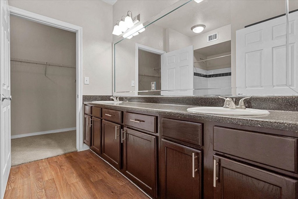 a bathroom with a sink and a mirror at The Clairborne Apartment Homes, Grand Prairie, TX