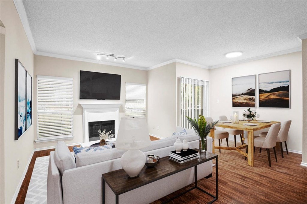 a living room with a fireplace and a dining room in the background at Creekview Apartment Homes, Texas