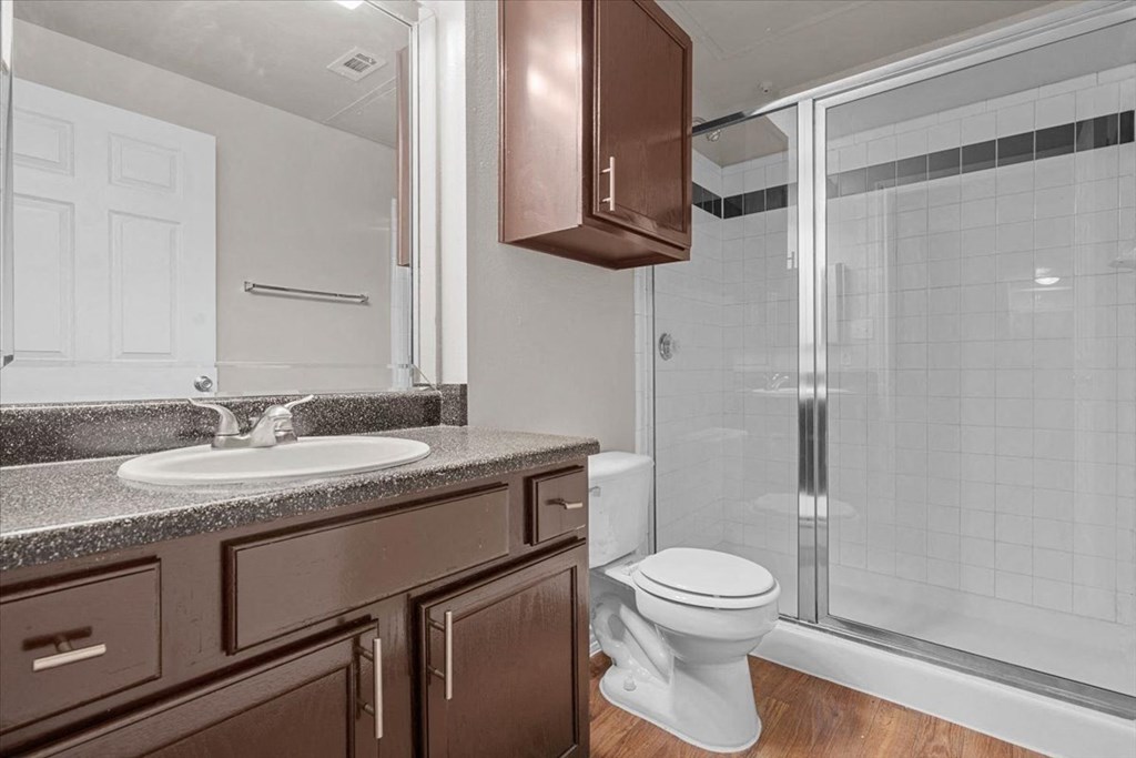 a bathroom with a toilet sink and shower at The Clairborne Apartment Homes, Grand Prairie