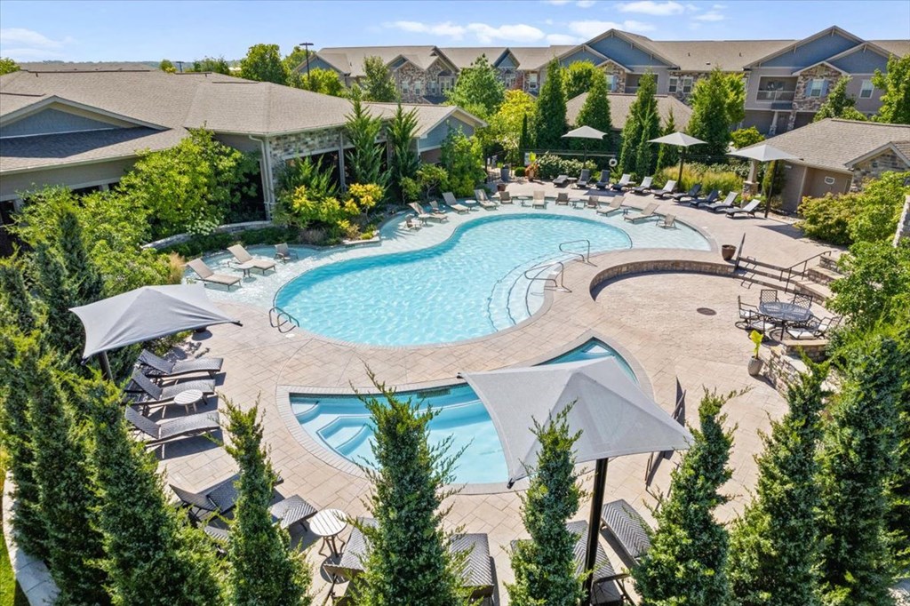 an aerial view of a resort style pool with chaise lounge chairs and umbrellas