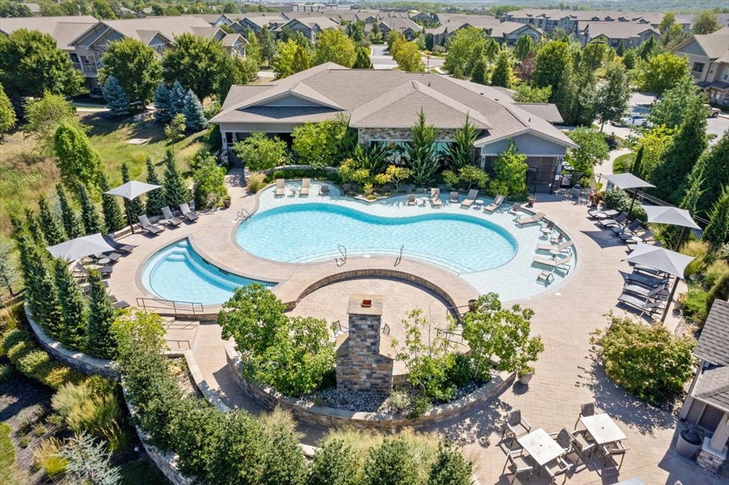 an aerial view of a resort style pool with chaise lounge chairs and umbrellas