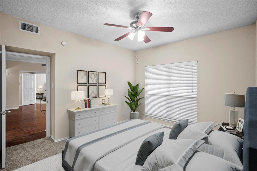 a bedroom with a large bed and a ceiling fan at Creekview Apartment Homes, Dallas