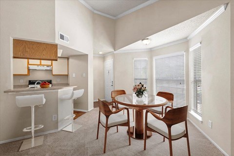 a dining area with a table and chairs and a kitchen in the background at Pear Ridge, Texas, 75287