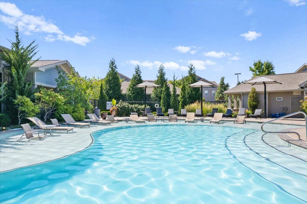 a swimming pool with chaise lounge chairs and umbrellas in front of a row of
