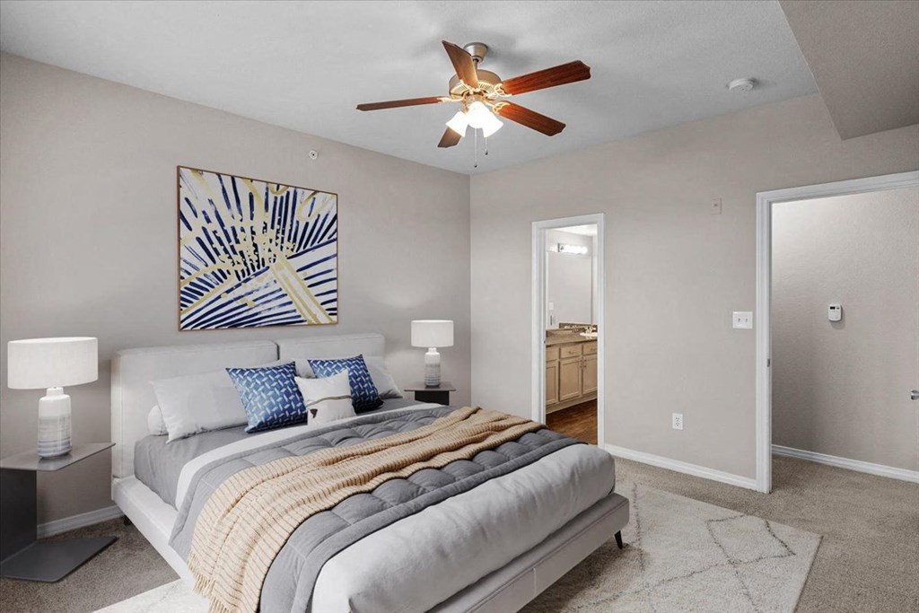 a bedroom with a large bed and a ceiling fan at The Clairborne Apartment Homes, Grand Prairie