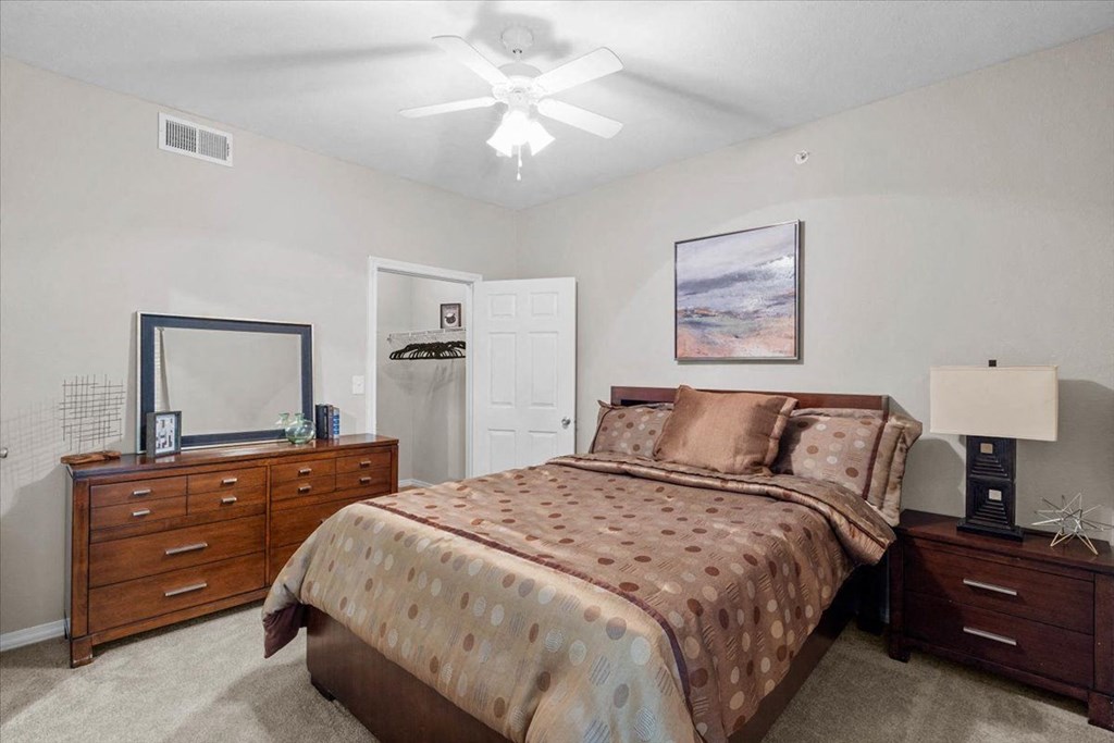 a bedroom with a bed and dresser at The Clairborne Apartment Homes, Grand Prairie