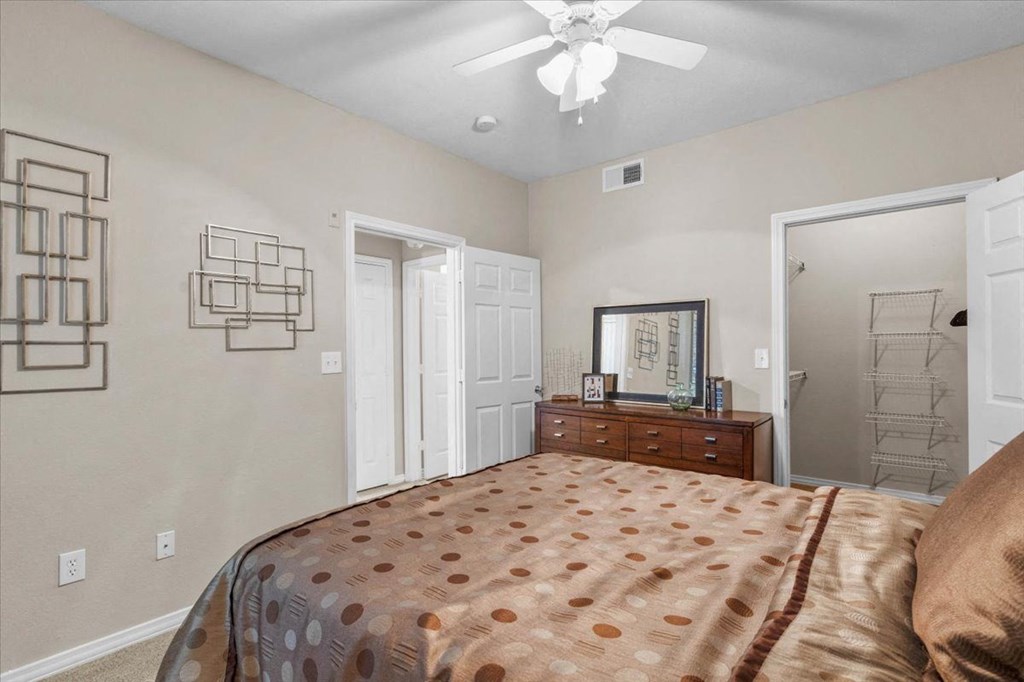 a bedroom with a bed and a ceiling fan at The Clairborne Apartment Homes, Grand Prairie, Texas