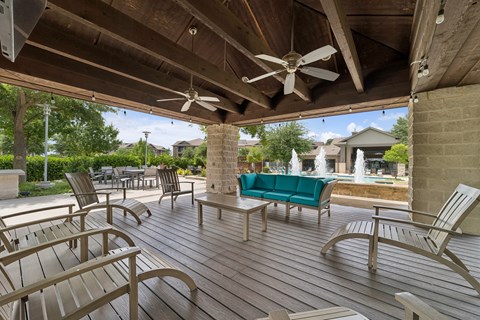 A wooden deck with a green couch and chairs.