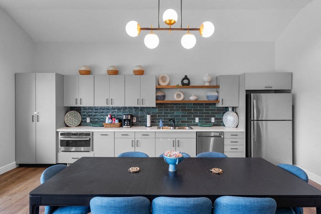a kitchen with white cabinets and a table with blue chairs
