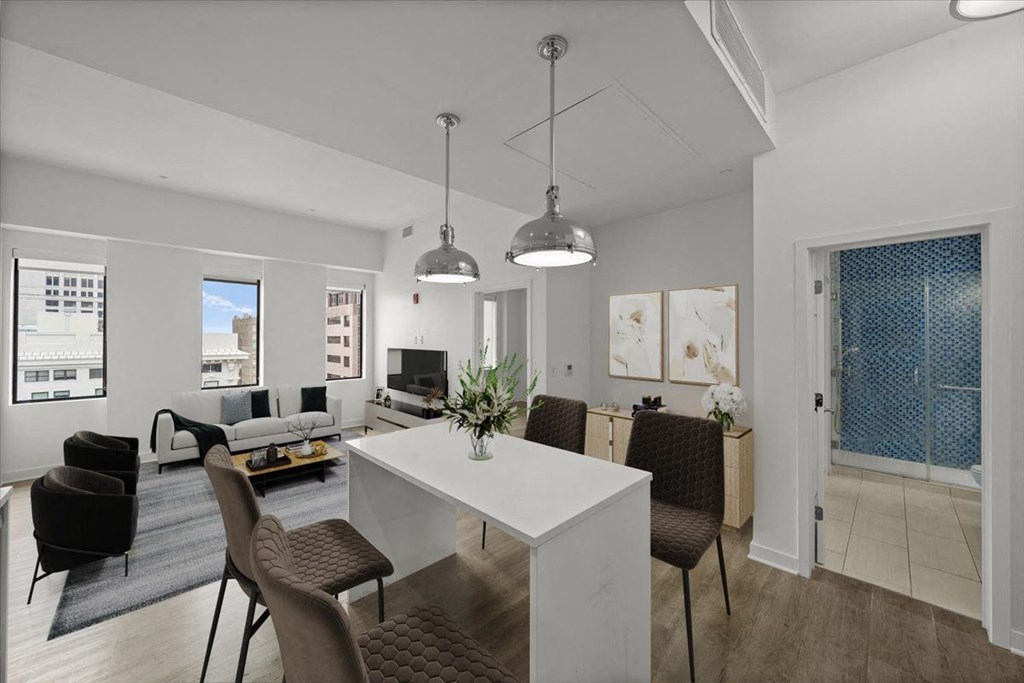 A modern dining room with a white table and brown chairs at Sky On Main Apartments, Missouri City 64105