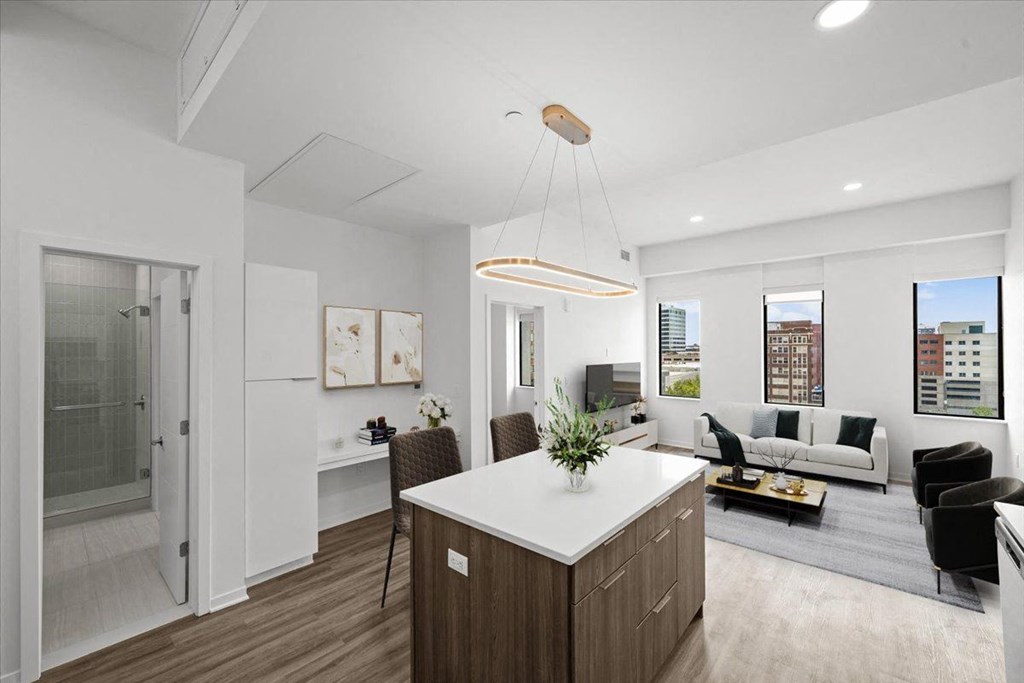 A modern kitchen with a white countertop and wooden cabinets. at Sky On Main Apartments, Missouri, 64105
