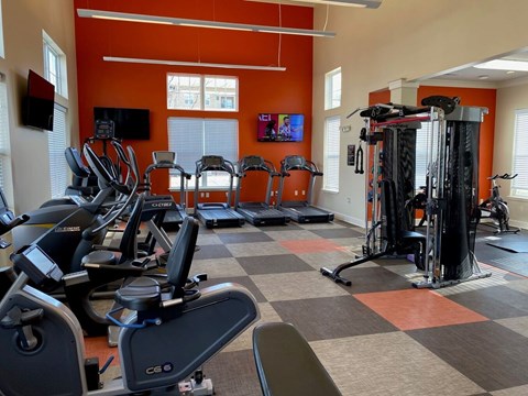 A gym with orange walls and a variety of exercise equipment.