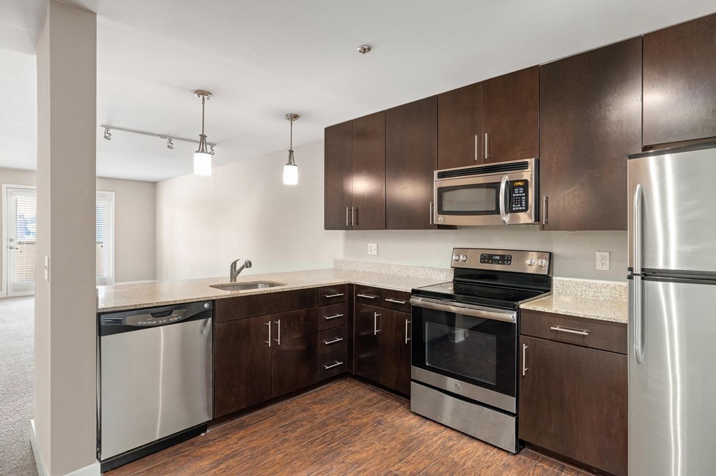 a kitchen with dark wood cabinets and stainless steel appliances at Cambria Luxury Apartment Homes, Missouri